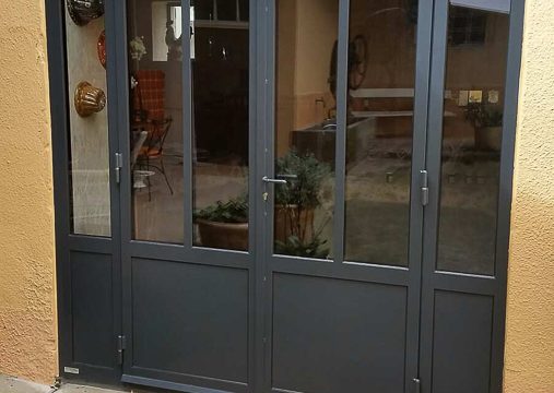 "Baie vitrée sur mesure avec cadre et porte noire, réalisation à Lyon."