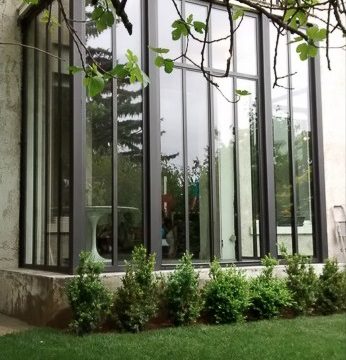"Véranda sur mesure et fenêtres en métal fabriquées à Lyon, installées dans une maison du Rhône."