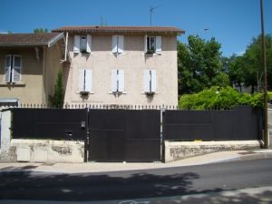 Une maison avec une clôture en métal noir devant.