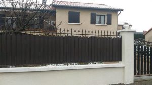 Une clôture métallique devant une maison.