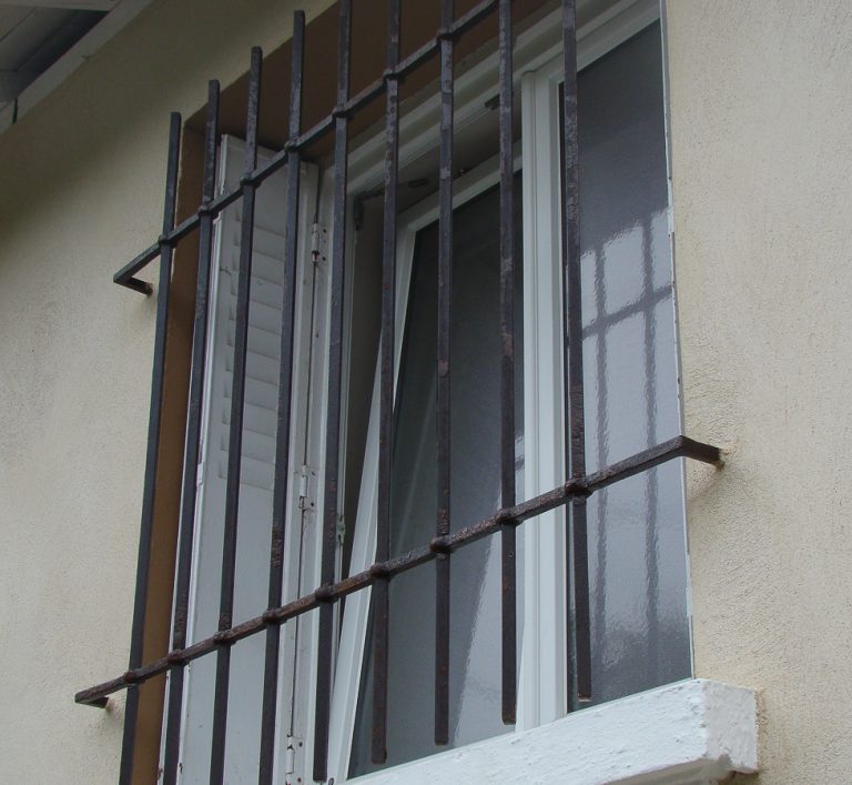 Une fenêtre en métal avec des barreaux en fer forgé.