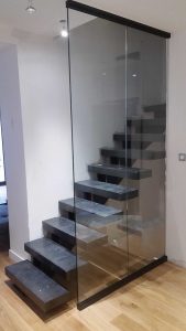 Un escalier en verre dans une pièce avec plancher de bois franc.