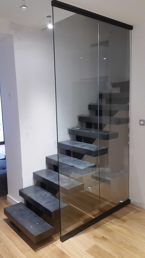 Un escalier en verre dans une pièce avec parquet en bois franc.