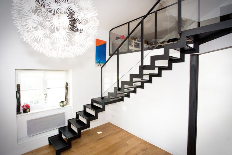 Escalier métallique personnalisé en noir avec garde-corps en verre, confectionné à Lyon par un artisan métallier de haute qualité spécialisé dans les réalisations sur mesure, dans le département du Rhône.