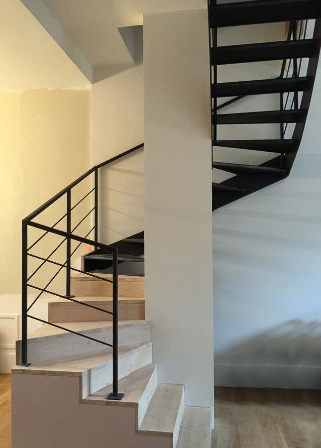 Escalier en spirale métallique, réalisé sur mesure par un artisan métallier de Lyon dans le Rhône, installé dans une pièce avec des sols en bois, symbolisant la grande qualité des produits fabriqués.