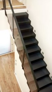 Un escalier noir avec garde-corps en verre dans une maison.