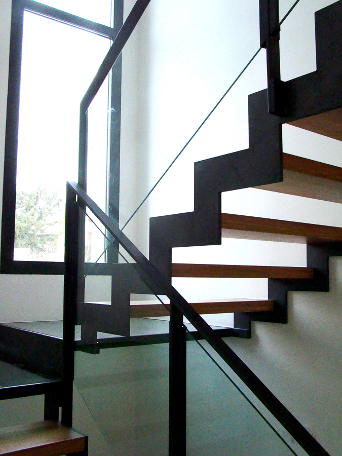 Un escalier métallique sur mesure avec une rampe en verre, réalisé par un artisan métallier de haute qualité basé à Lyon, dans le département du Rhône.