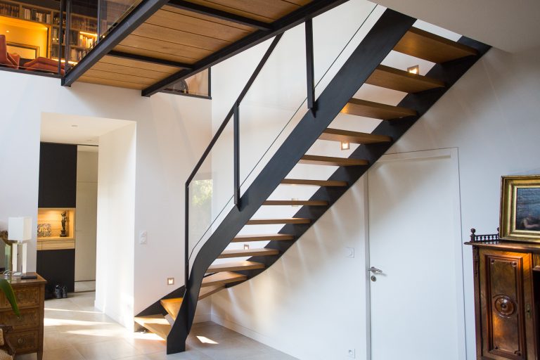 Un escalier métallique sur mesure, de grande qualité, fabriqué par notre artisan métallier basé à Lyon, dans le Rhône, menant à une pièce dans une maison.