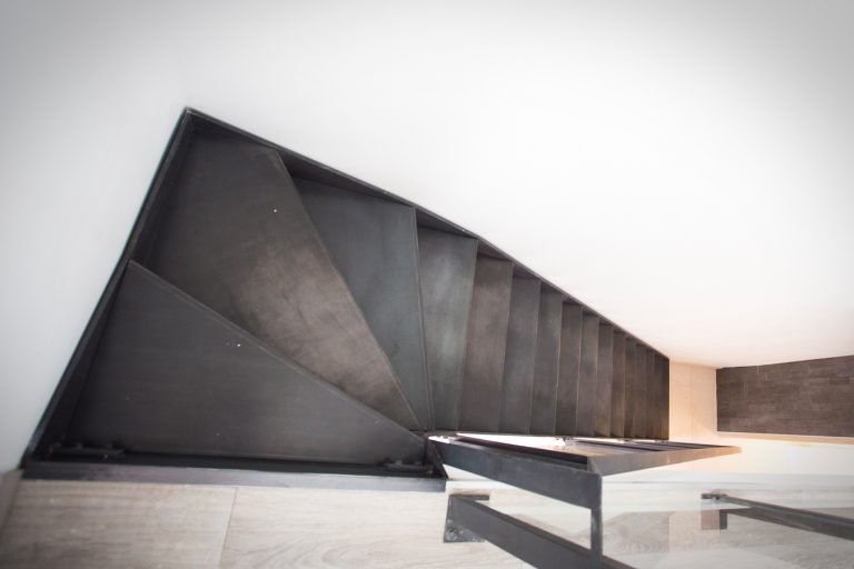 Escalier sur mesure en métal, avec une rampe artisanale, dans une pièce d'une maison à Lyon. Création réalisée par notre artisan métallier local dans le département du Rhône reflétant son savoir-faire en garantissant qualité et précision.