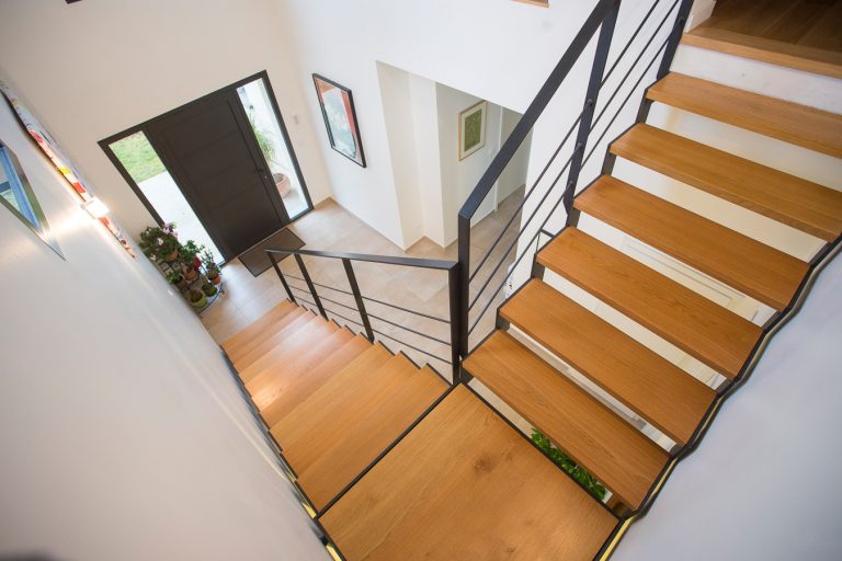 Escalier métallique sur mesure, d'excellente qualité, réalisé par notre artisan métallier basé à Lyon, dans le Rhône, menant à une porte dans une maison.