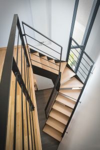 Un escalier avec une balustrade noire et un plancher en bois.