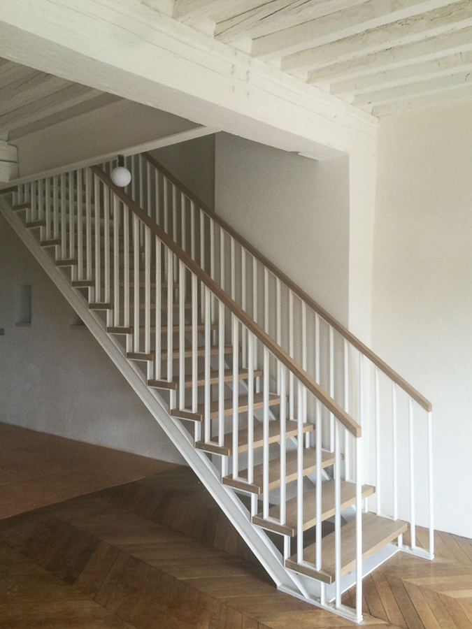 Escalier métallique blanc sur mesure dans une pièce vide, réalisé par un artisan métallier de Lyon, Rhône, démontrant le haut niveau de qualité et de finition.
