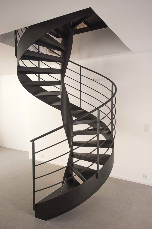Une splendide réalisation sur mesure d'un escalier en spirale métallique noir par un expert artisan métallier, basé à Lyon dans le département du Rhône, témoignant de la grande qualité de son travail.