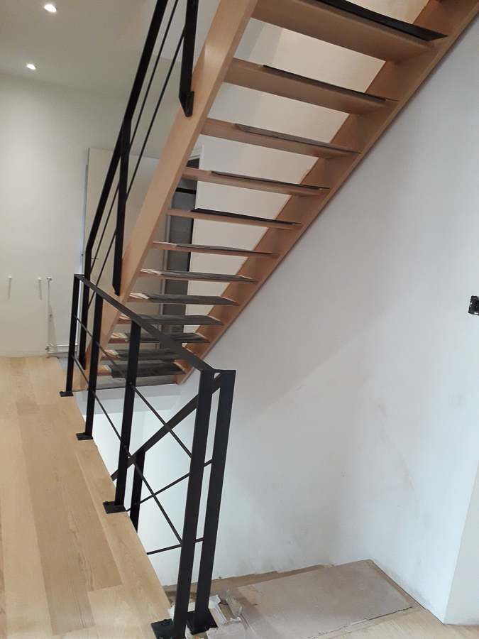 Un escalier avec une rampe en métal et un plancher en bois.