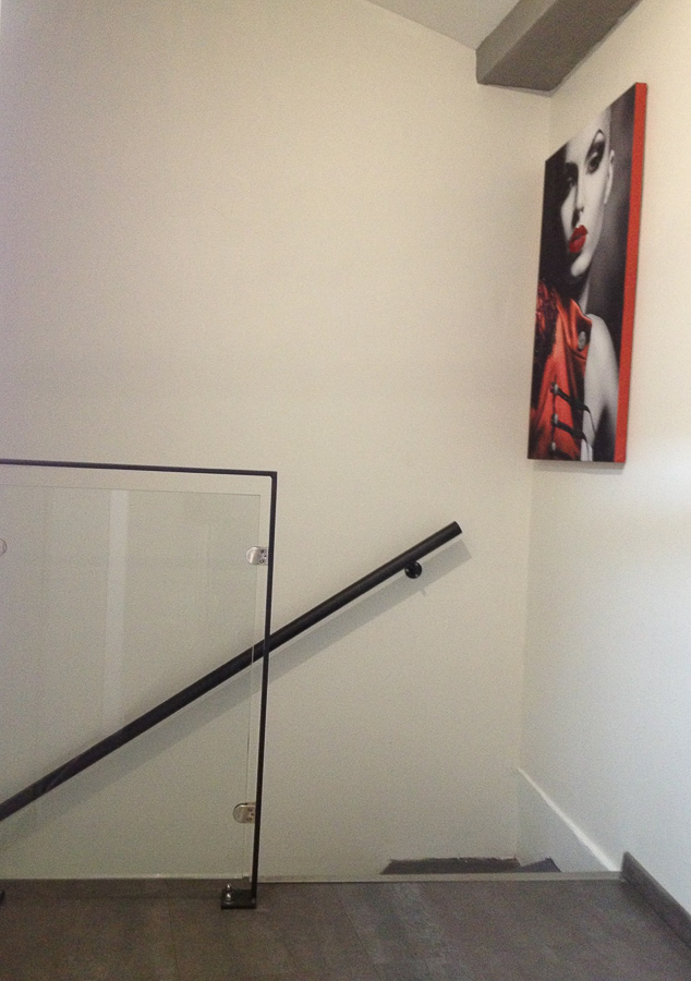 Un escalier avec une rampe en métal noir et un tableau au mur.