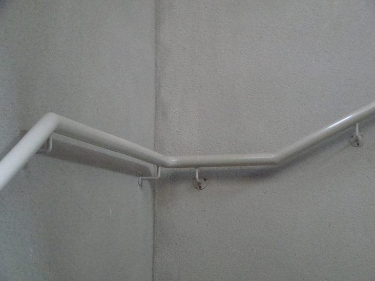 Une rampe d'escalier blanche avec un crochet attaché.