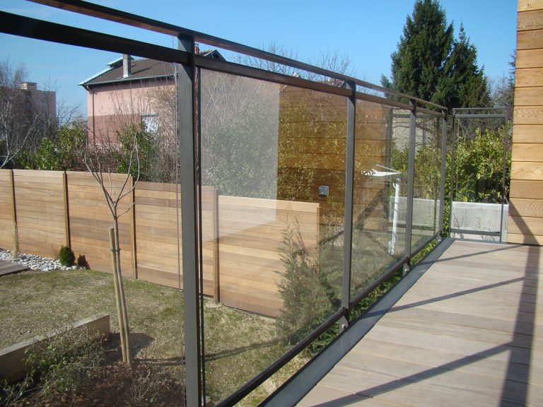 Une terrasse en bois avec un garde-corps en verre.