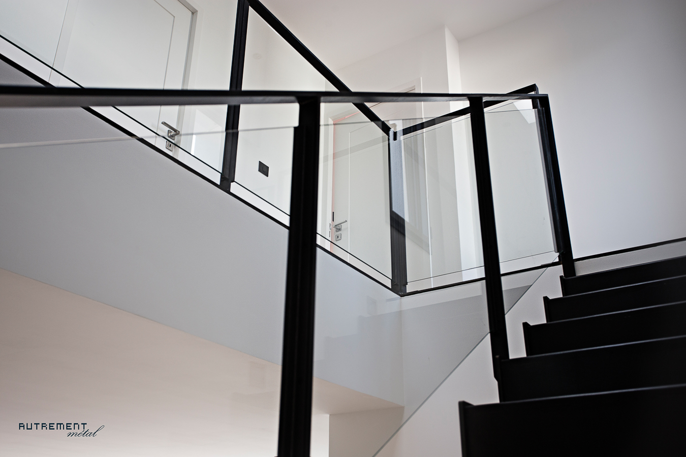 Une rampe d'escalier en verre dans une maison blanche.
