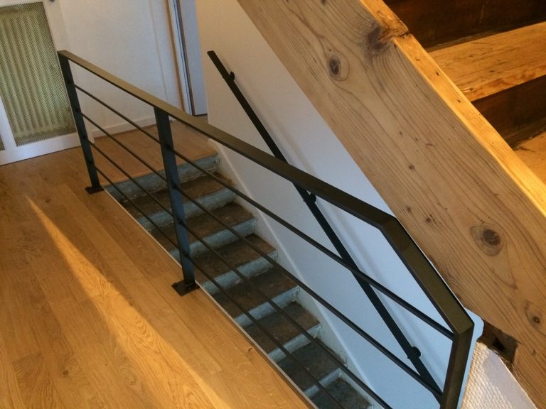 Un escalier avec une rampe en métal et un plancher en bois.