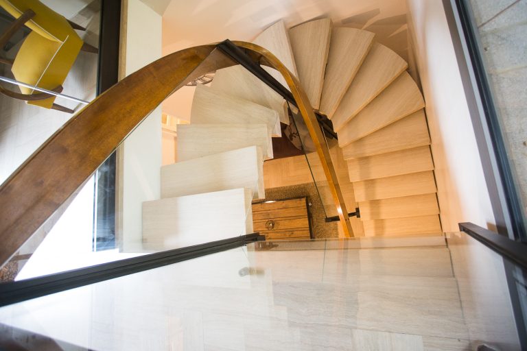 Un escalier en colimaçon avec une main courante en bois.