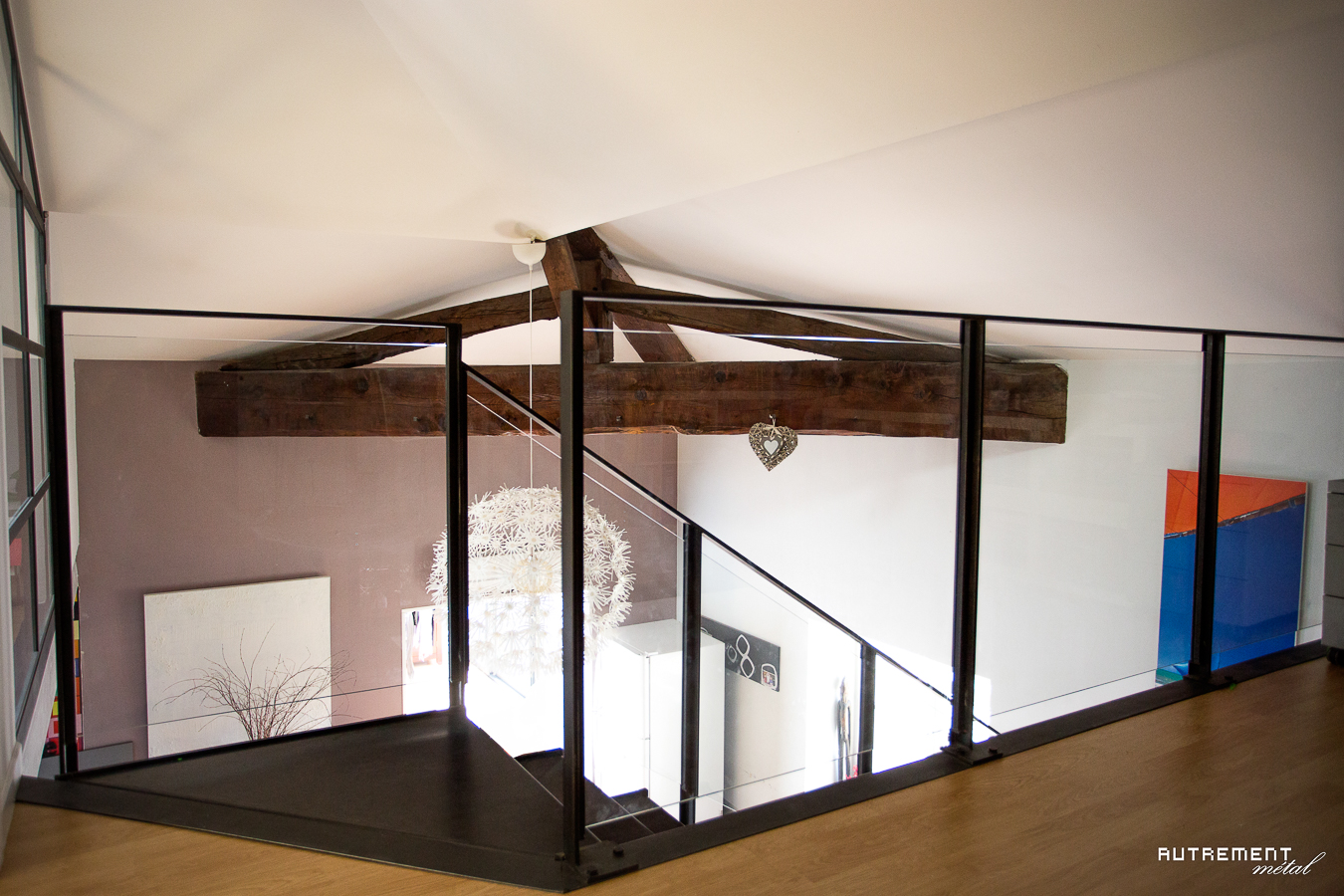 Une pièce avec un parquet en bois et une balustrade en verre.