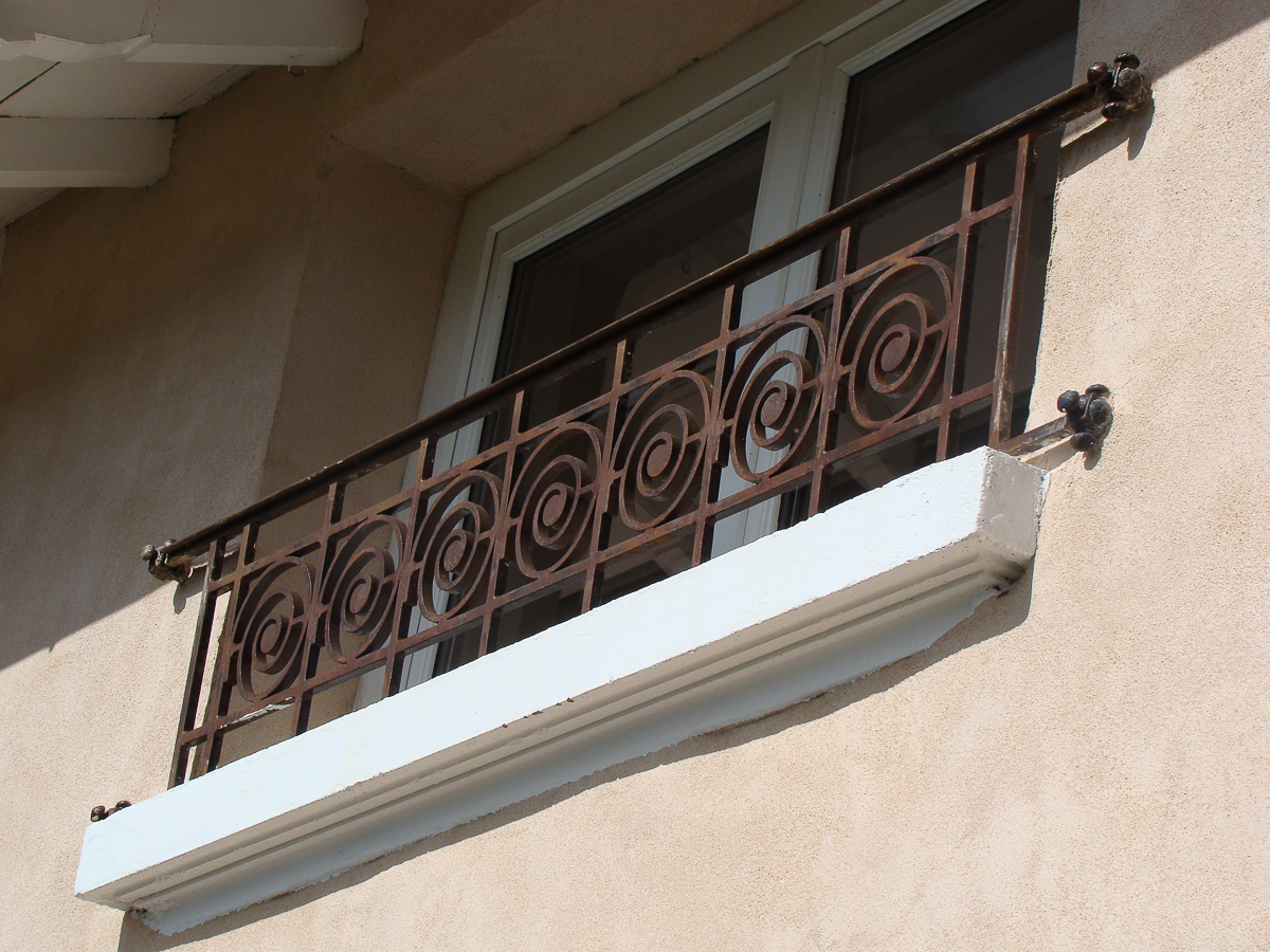 Une fenêtre avec une balustrade décorative en fer forgé en métal.