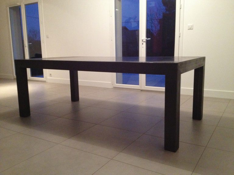 Une table à manger noire en métal dans une pièce avec portes coulissantes en verre.