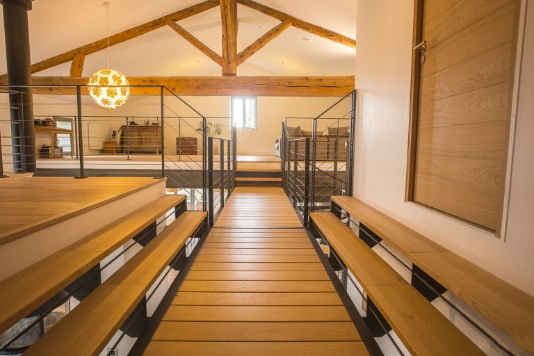 Un escalier en bois menant à une pièce avec des bancs en bois.