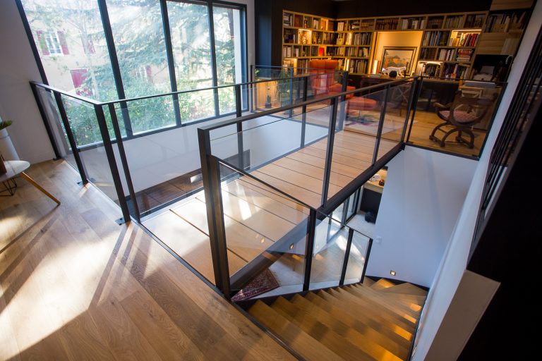 Un escalier avec garde-corps en verre dans un salon.