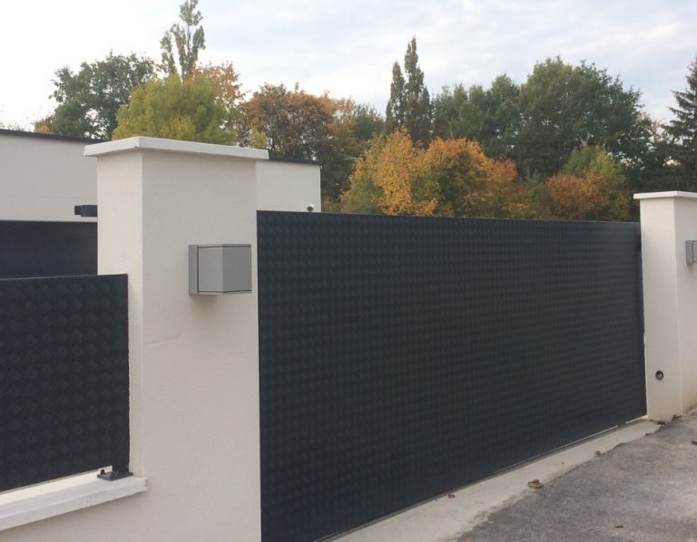 Une clôture métallique avec un portail noir.