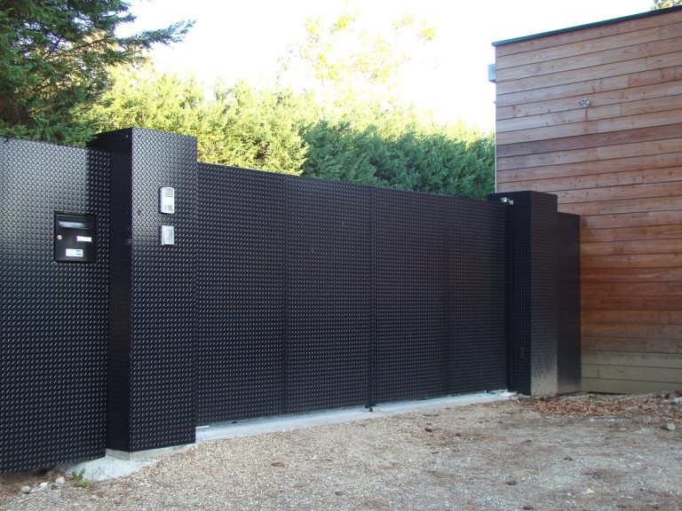 Un portail métallique devant une maison.