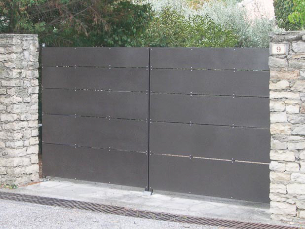 Un portail métallique orné d'un mur en pierre.