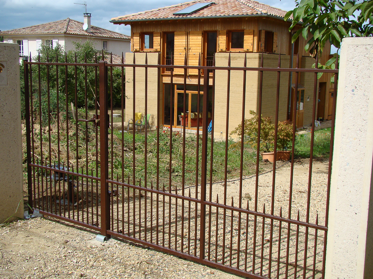 Un portail métallique devant une maison.