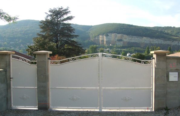 Un portail en métal blanc devant une maison.