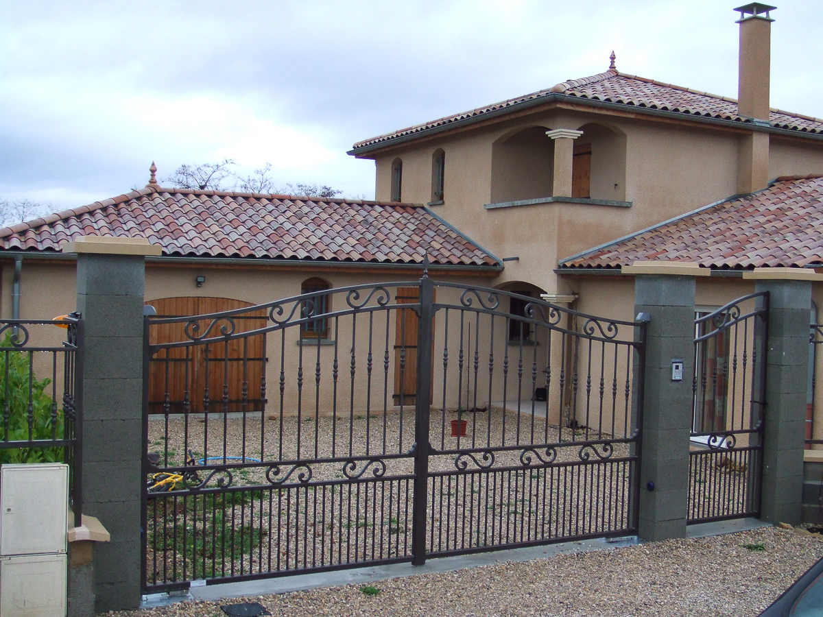 Un portail métallique devant une maison.