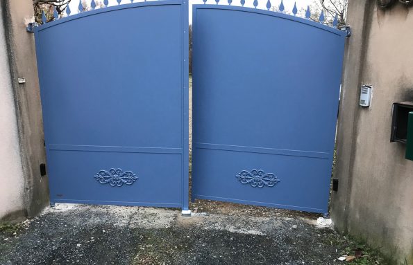 Une paire de portes bleues en métal devant une maison.