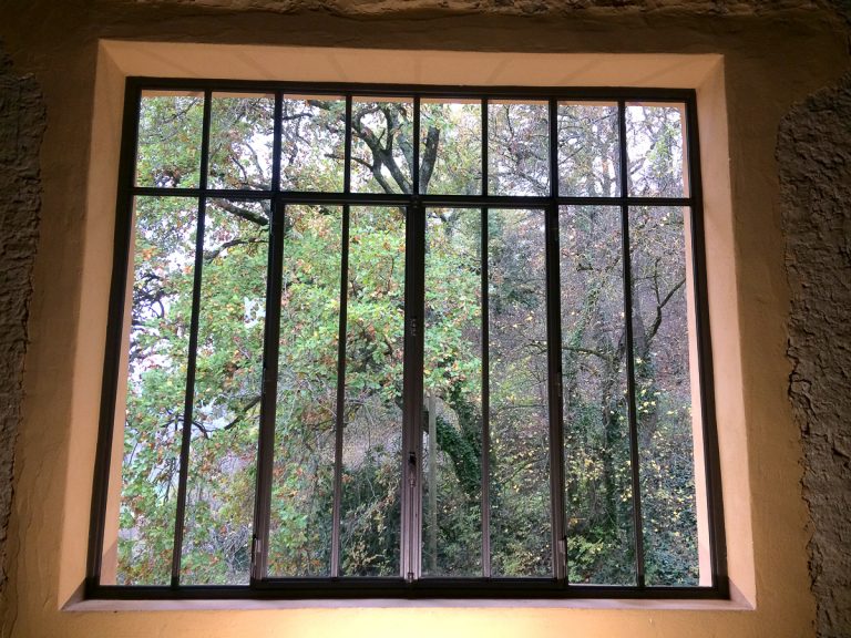 Une fenêtre dans une pièce avec des barreaux en fer forgé.