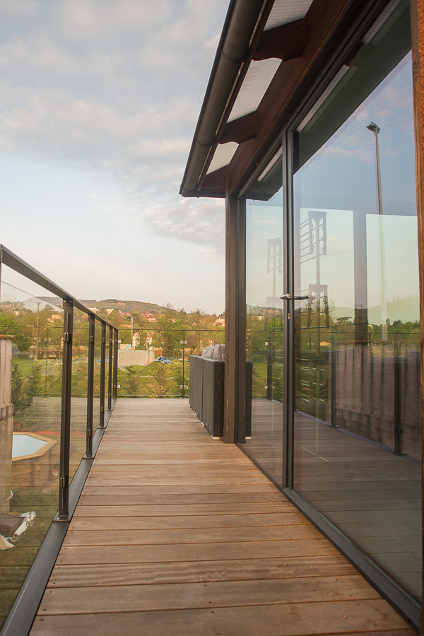 Une terrasse en bois avec un garde-corps en verre.