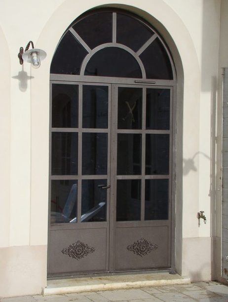Une porte métallique avec une fenêtre cintrée.