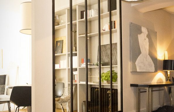 Un salon avec parquet et porte vitrée encadrée de métal.