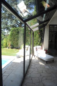 Une terrasse vitrée avec une piscine en métal.