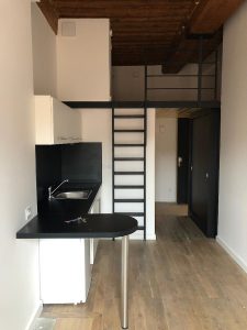 Un petit appartement avec un escalier métallique.