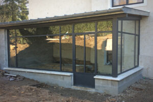 Une maison métallique en construction avec une grande fenêtre en verre.
