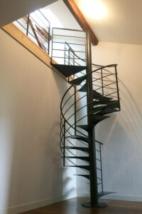 Un escalier en colimaçon dans une pièce avec un sol métallique.