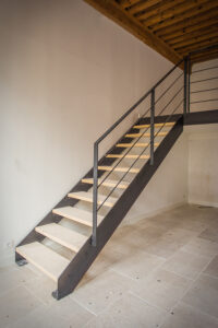 Un escalier métallique dans une pièce avec parquet.