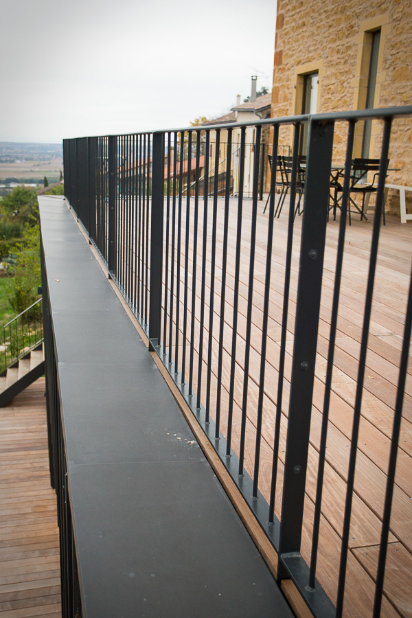 Une balustrade métallique sur une terrasse en bois.