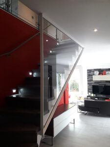 Un escalier métallique dans un salon aux murs rouges.