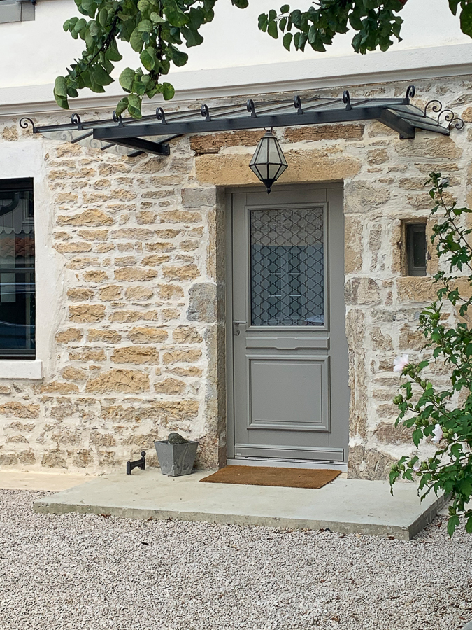 Une maison en pierre avec une porte et une fenêtre en métal.