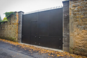 Une porte noire en métal sur un mur de pierre.