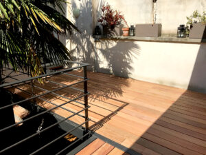 Une terrasse en bois avec une balustrade en métal et une plante en pot.